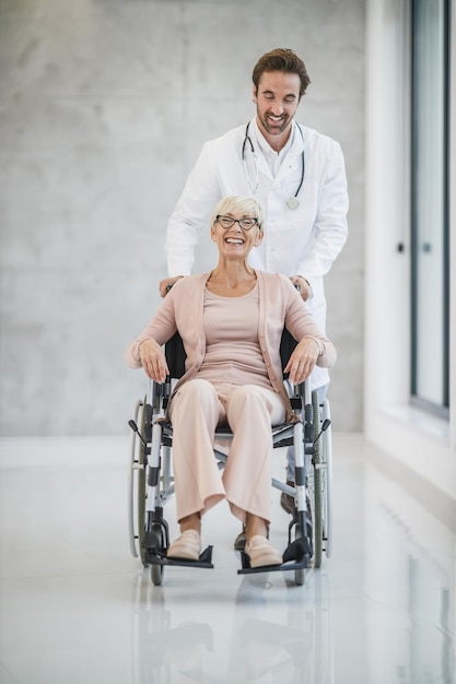 Photo d'un jeune médecin qui s'occupe d'une patiente âgée en fauteuil roulant.