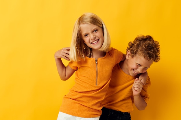 Photo de jeux de vêtements décontractés pour garçons et filles positifs s'amusant ensemble posant sur fond coloré