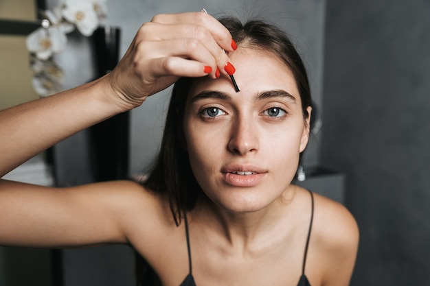 Photo de jolie femme des années 20 avec de longs cheveux noirs debout dans la salle de bain