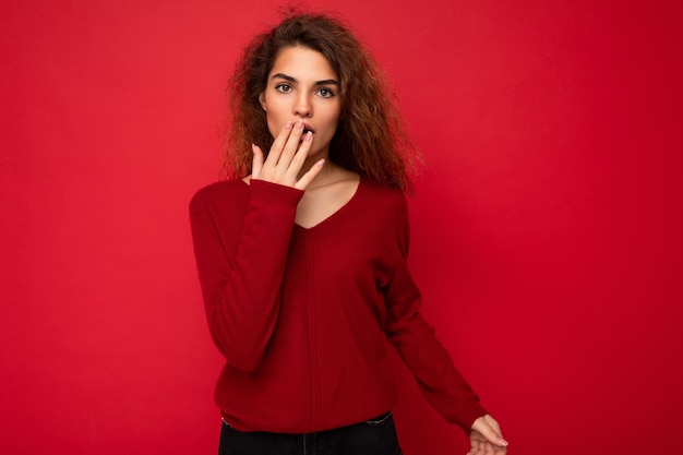 Photo d'une jolie femme brune bouclée étonnée et étonnée avec des émotions sincères portant des vêtements décontractés