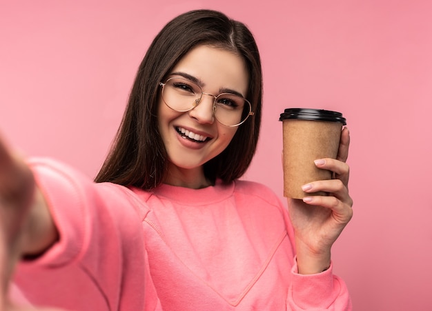 Photo de jolie femme dans des verres tient du café et prend selfie