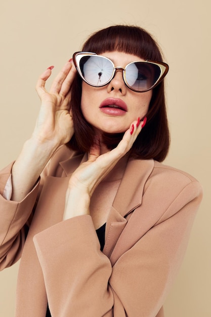 Photo jolie femme dans une veste beige style élégant lunettes de soleil fond isolé