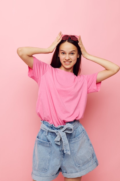 Photo jolie femme lunettes roses et tshirt geste de la main fond rose