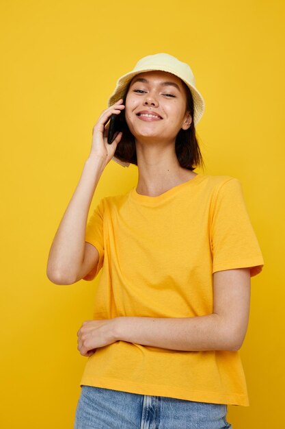 Photo jolie fille dans un chapeau jaune Style jeunesse décontracté parlant au téléphone Style de vie inchangé