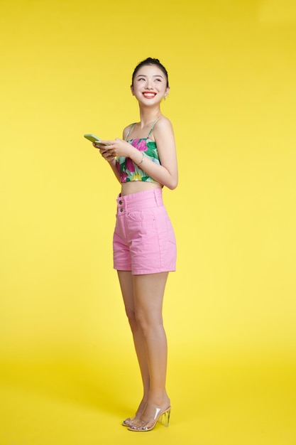 Photo d'une jolie fille excitée habillée en haut recadrée lisant un téléphone portable isolé sur fond jaune