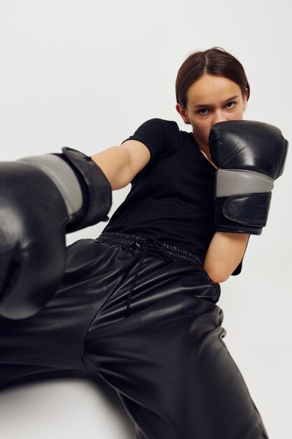 Photo jolie fille en gants de boxe sur le sol en tshirt noir fond clair