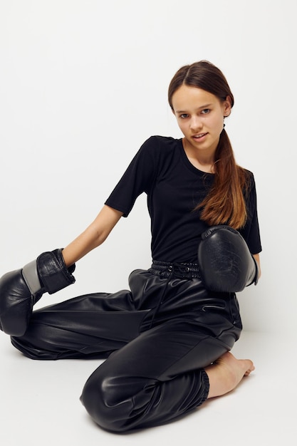 Photo jolie fille en gants de boxe sur le sol en tshirt noir fond clair