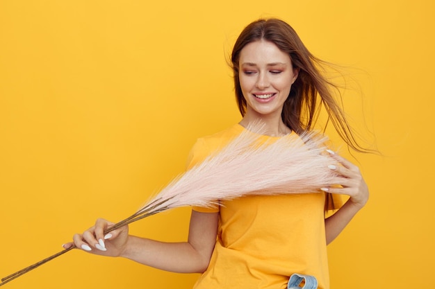 Photo jolie fille posant des plumes roses dans les mains charme fashion ouais fond jaune