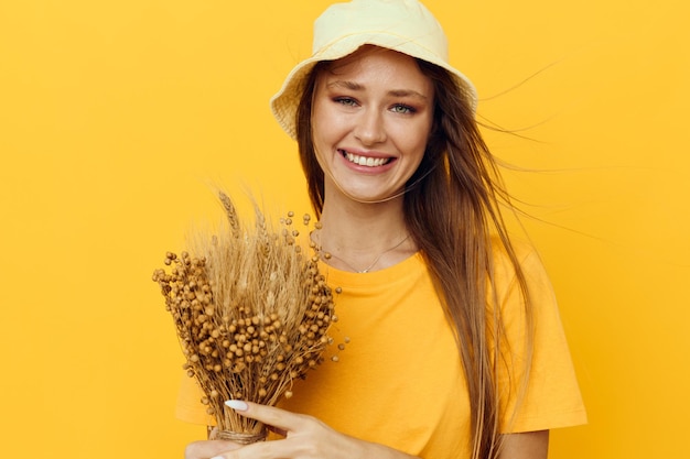 Photo jolie fille en T-shirts jaunes fleurs séchées dans les mains fond isolé