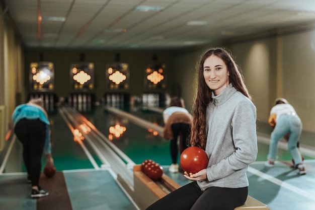 Photo d'une jolie fille tenant une boule de bowling au club de bowling et regardant la caméra.