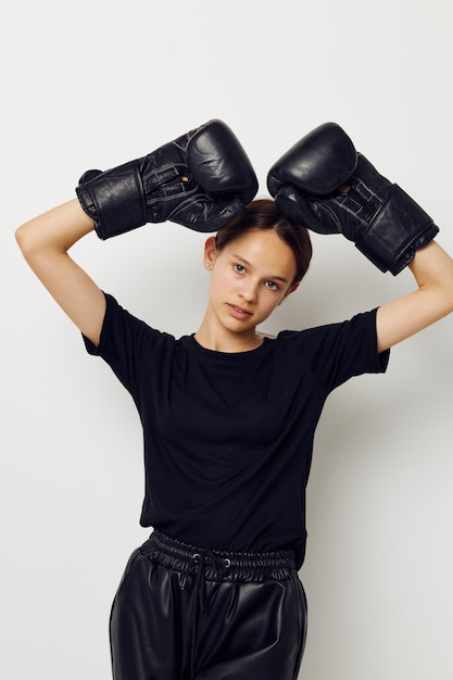 Photo jolie fille en uniforme de sport noir gants de boxe posant mode de vie inchangé