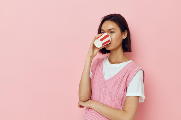 Photo jolie fille verre à boire jetable dans un Tshirt rose fond rose