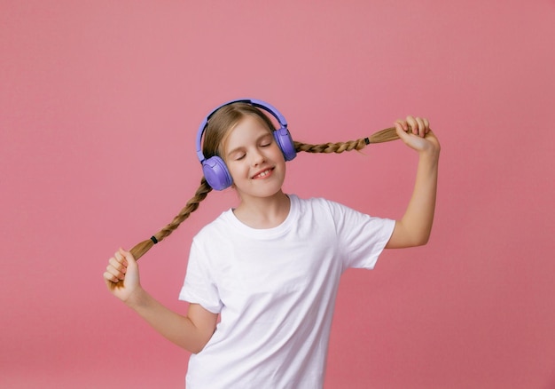 Photo d'une jolie jeune adolescente drôle dans un casque de cavalier rose dansant en écoutant de la musique sur un fond