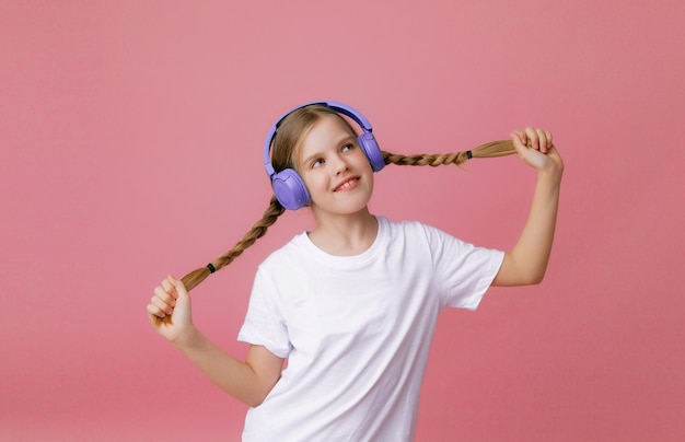 Photo d'une jolie jeune adolescente drôle dans un casque de cavalier rose dansant en écoutant de la musique sur un fond