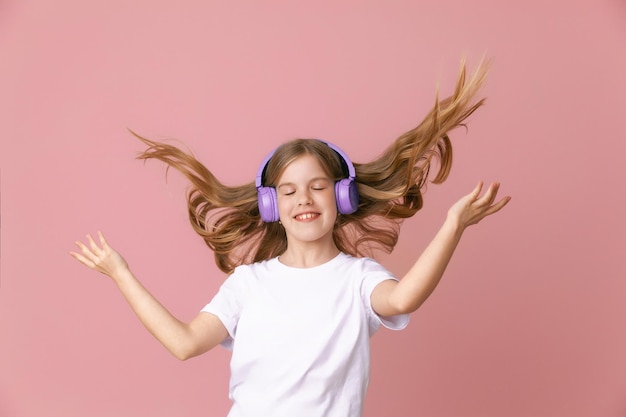 Photo d'une jolie jeune adolescente drôle dans un casque de cavalier rose dansant en écoutant de la musique sur un fond