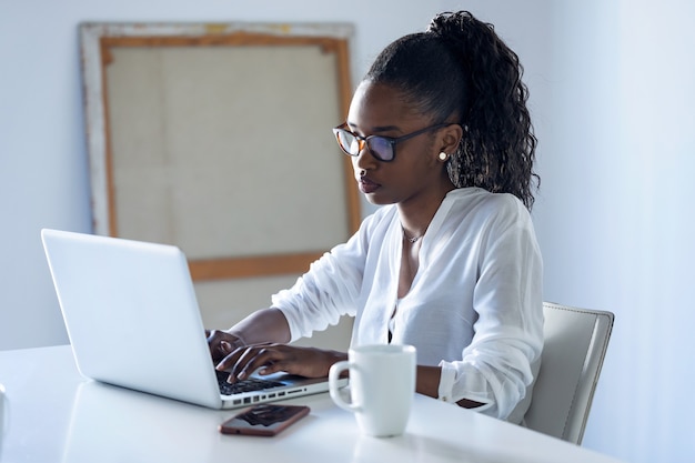 Photo d'une jolie jeune femme d'affaires travaillant avec un ordinateur portable au bureau.