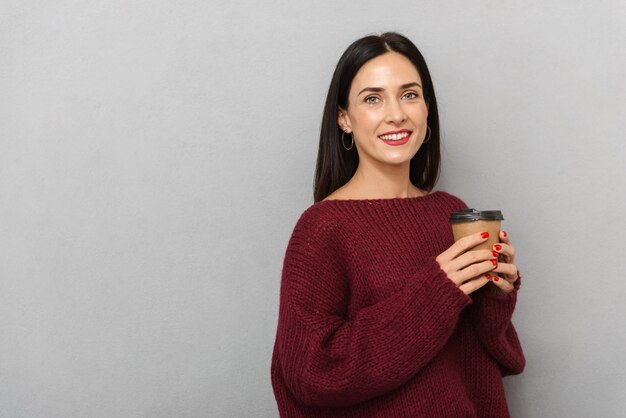 Photo de jolie jeune femme habillée en pull bordeaux isolé de boire du café.