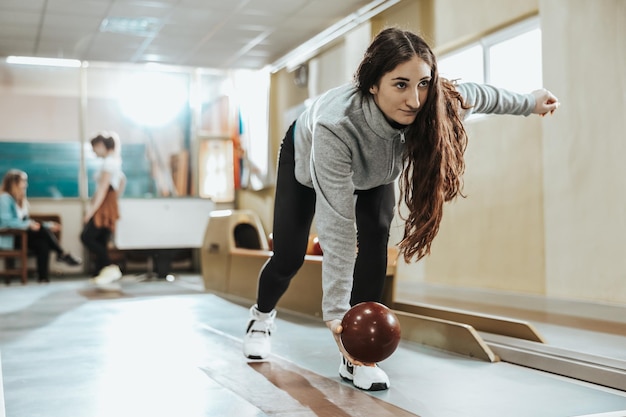 Photo d'une jolie jeune femme lançant la boule de bowling.