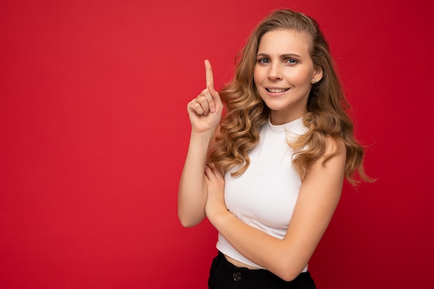 Photo d'une jolie jeune femme surprise étonnée pointant le doigt vers le fond présentant des annonces