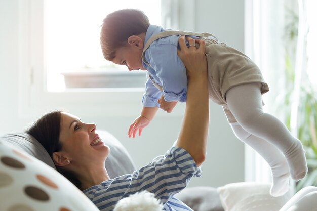 Photo d'une jolie jeune mère avec son bébé jouant et aimant dans le salon à la maison.