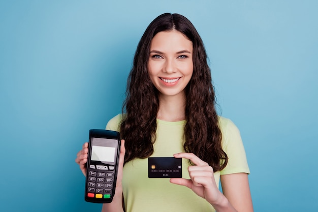 Photo de joyeuse caissière tenir le terminal nfc de carte de crédit sur fond bleu