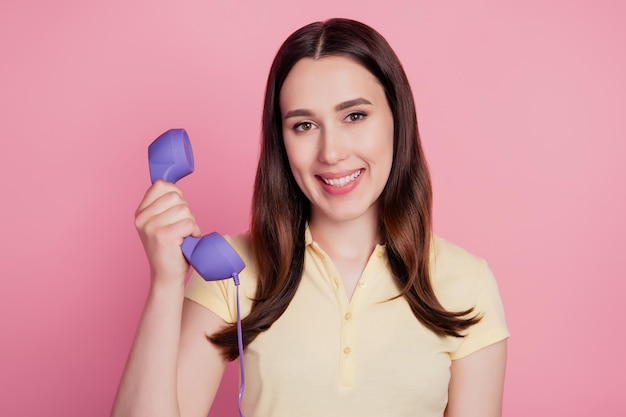 Photo de joyeuse dame positive tenir le téléphone passer un appel fixe sur fond rose