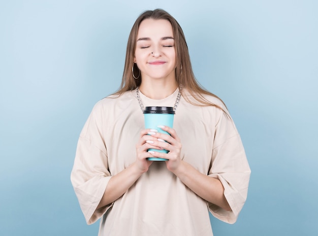 Photo de joyeuse jolie petite amie positive tenant une tasse de café à emporter souriant avec les yeux fermés isolé sur fond de couleur vive