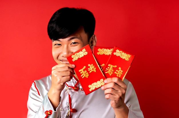 Photo joyeux nouvel an chinois homme asiatique tenant des distiques du nouvel an chinois sur fond rouge