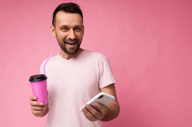 Photo de joyeux souriant beau jeune homme brune mal rasé avec barbe portant du rose clair tous les jours