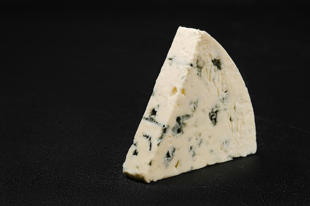 Photo macro de morceau de fromage avec moisissure bleue sur fond noir