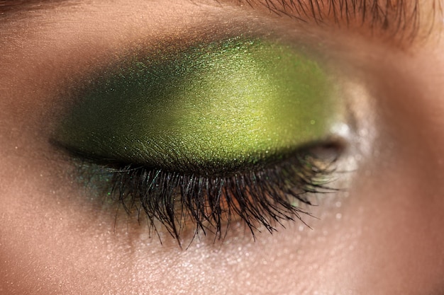 Photo macro d'un œil fermé avec du maquillage de couleurs vertes. tourné en studio. horizontal.