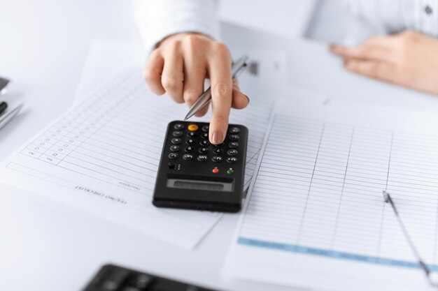 photo de main de femme avec calculatrice et papiers