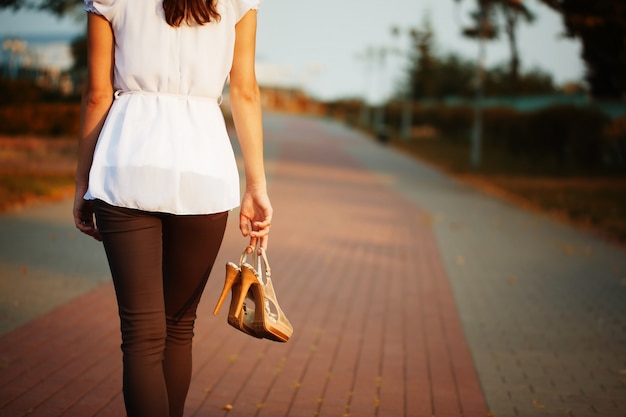 Photo de la main de la jeune femme avec des chaussures dans le parc.