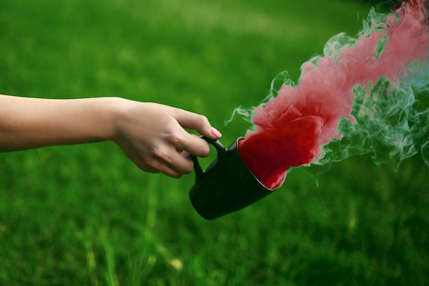 Photo de la main avec une tasse et de la fumée rouge