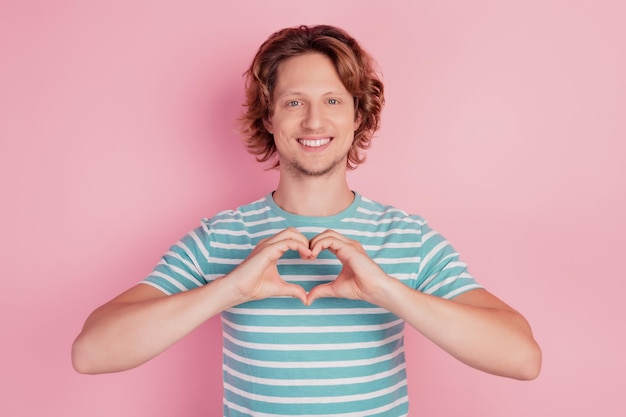 Photo de mains d'homme romantique montrant un geste cardiaque portant un t-shirt rayé bleu décontracté sur fond rose