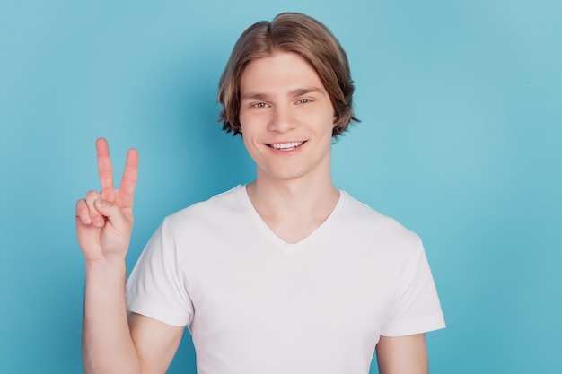 Photo de mains de jeune homme montrent v-sign isolé sur fond bleu