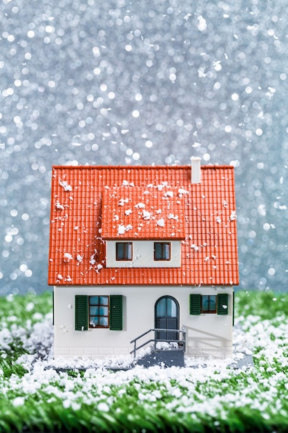 Photo de maison de jouet avec des chutes de neige sur une surface grise