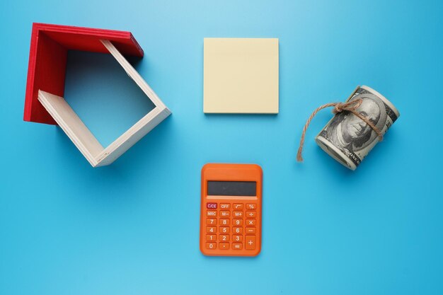 Une photo de maison miniature avec bloc-notes et calculatrice pour le concept de propriété immobilière