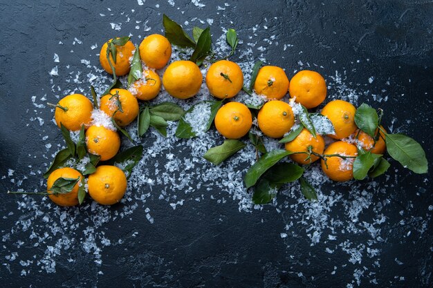 Photo de mandarines sur table noire avec de la neige