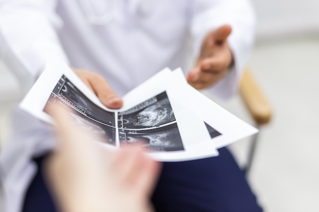Photo d'un médecin portant un manteau de laboratoire donnant un résultat d'échographie à son patient