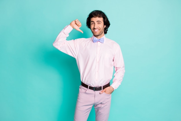 Photo d'un mignon homme bouclé brunet habillé en tenue rose pointant le doigt du pouce lui-même isolé sur fond de couleur sarcelle