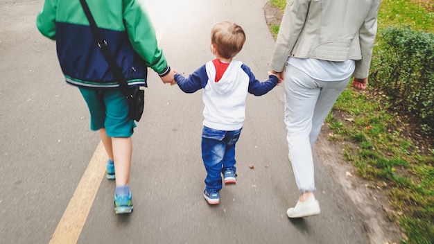 Photo d'un mignon petit garçon de 3 ans marchant avec sa famille dans un parc en automne