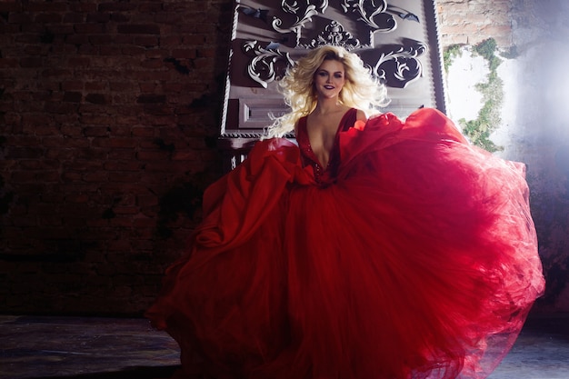 Photo de mode de jeune femme magnifique. Courir vers la caméra. Blonde séduisante en robe rouge avec une jupe moelleuse