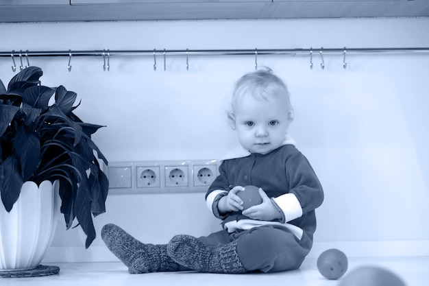 Photo monochrome d'un petit enfant blond dans la cuisine assis sur une table