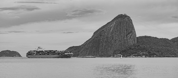 Photo de la montagne du pain de sucre avec un navire de cargaison qui passe devant elle dans la baie de Guanabara