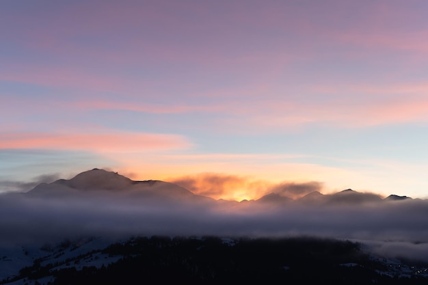 Photo des montagnes et de la brume à Falera, une municipalité de la région de Surselva, en Suisse au coucher du soleil