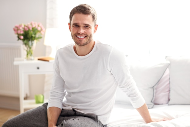 Photo montrant un jeune homme assis sur le lit le matin