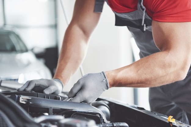 Photo photo montrant un travailleur de service de voiture musclé réparant un véhicule