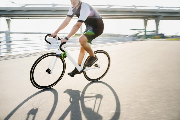 Une photo en mouvement d'un homme sur un vélo de route dans un casque portant des vêtements de cyclisme pour l'entraînement