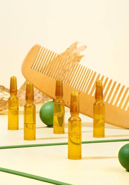 Photo de nature morte créative moderne Ampoules cosmétiques avec sérum pour la restauration de la croissance des cheveux Peigne à cheveux accessoires verts sur fond beige Concept beauté cheveux Selfcare spa et bien-être